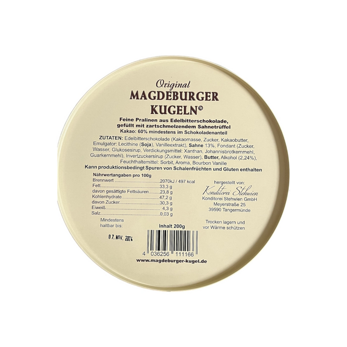Runde Packung 'Original Magdeburger Kugeln' mit Zutatenliste und Nährwertangaben. Enthält Edelbitterschokolade mit Sahnetrüffelfüllung. Verpackung zeigt Haltbarkeitsdatum, Herstellerangaben und Barcode. Authentische Pralinen aus Magdeburg.