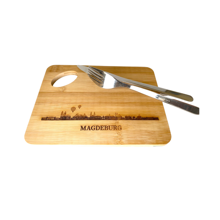 Vesperbrettchen aus Holz mit eingravierter Skyline von Magdeburg, stilvoll präsentiert mit Messer und Gabel, nachhaltiges Design, ideal für den Magdeburg-Fan.